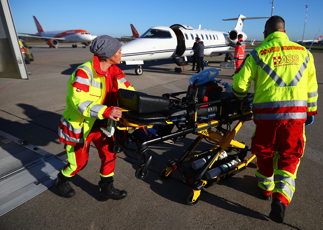 Zwei Rettungskräfte schieben eine Patinententrage zum Flugzeug.