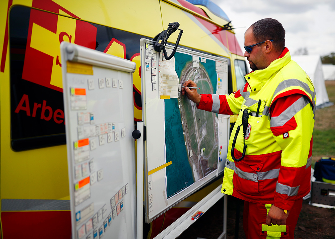 Samariter in Einsatzkleidung zeichnet eine Position auf dem Lageplan ein.