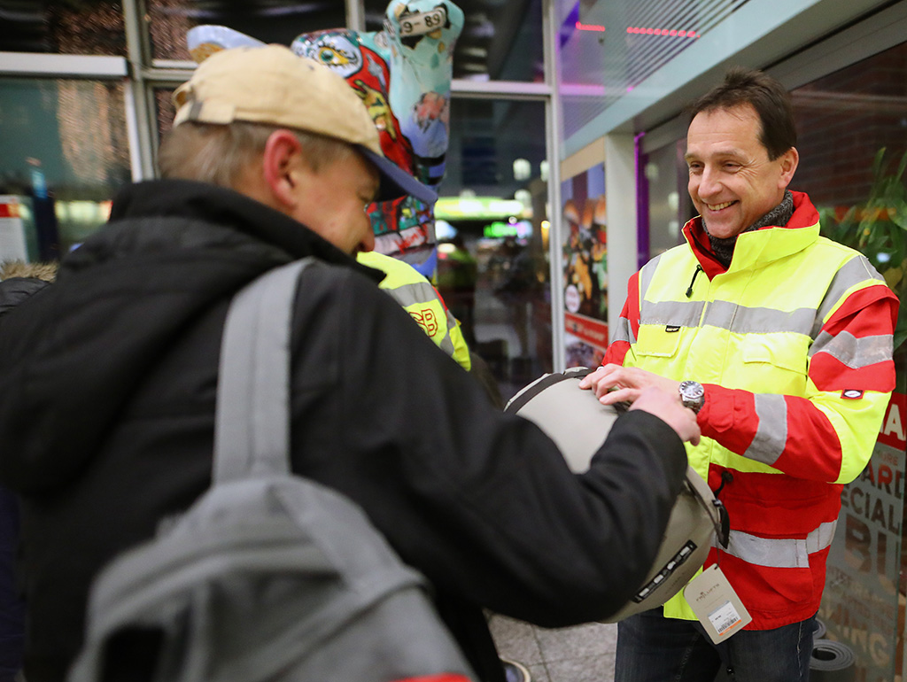 Samariter reicht wohnungslosem Menschen einen Schlafsack