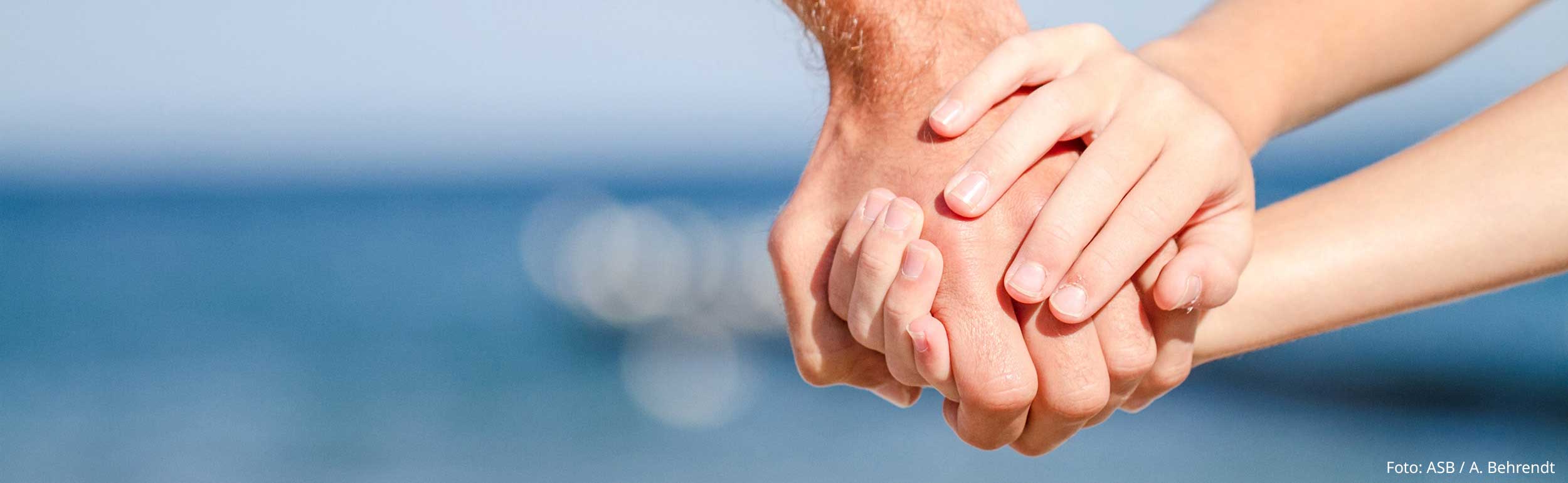 Erwachenen- und Kinderhand verbunden am Strand