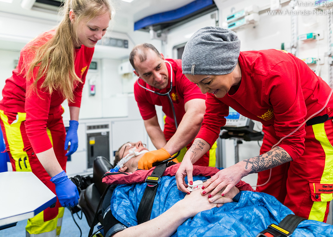 Gestellte Aufnahme: Drei Rettungskräfte versorgen einen Patienten im Fahrzeug.