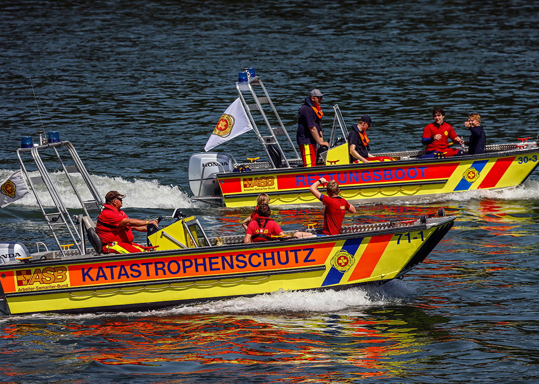 Zwei Rettungsboote mit Besatzung fahren auf dem Fluss.