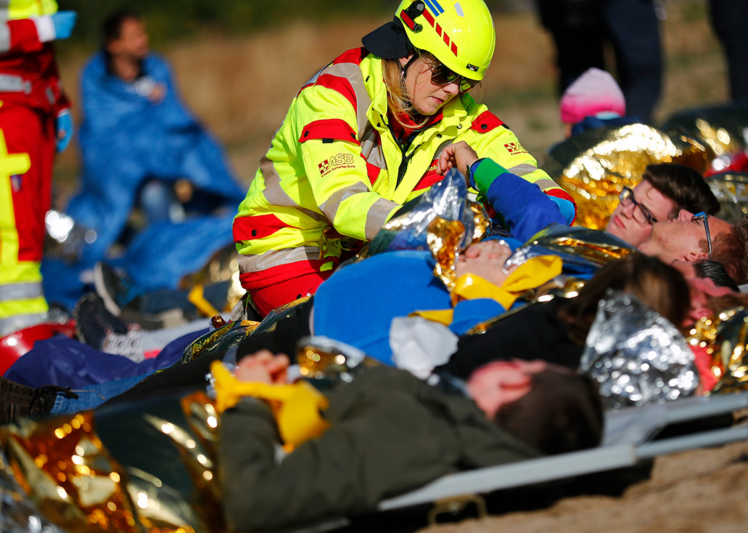 Mehrere Verletztendarsteller:innen auf Tragen werden von Sanitäterin versorgt.