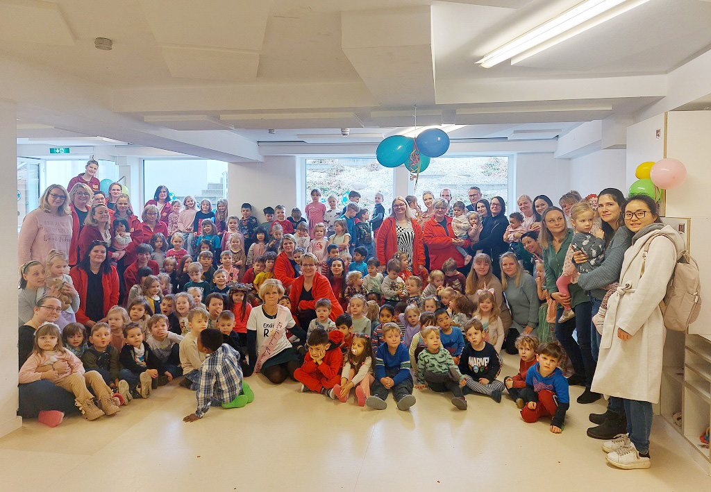 Die Kinder und das Team sitzen um Sabine herum auf dem Boden der Kita.